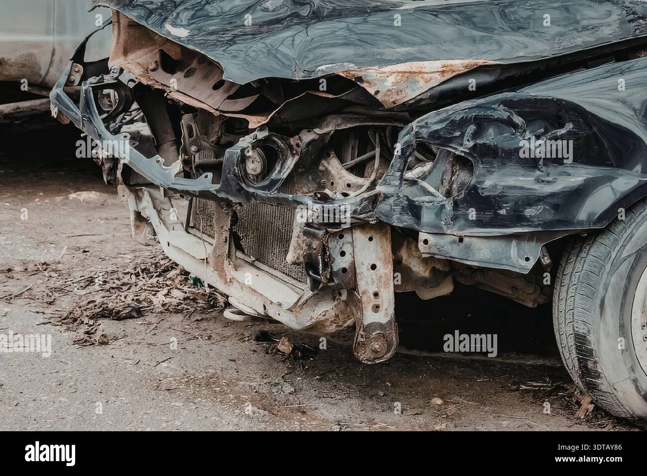 Das Bild zeigt eine Nahaufnahme einer beschädigten Fahrzeugfront mit einer zerknitterten Motorhaube, defekten Scheinwerfern und einem verbeulten Stoßfänger, was auf einen schweren Unfall hinweist. Stockfoto