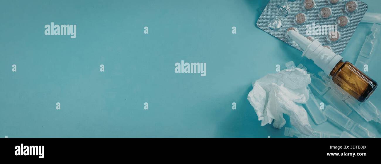 Das Bild zeigt eine Nahaufnahme einer Blisterpackung mit Pillen und einer kleinen Flasche Medizin auf blauem Hintergrund mit einem zerknitterten Gewebe. Stockfoto