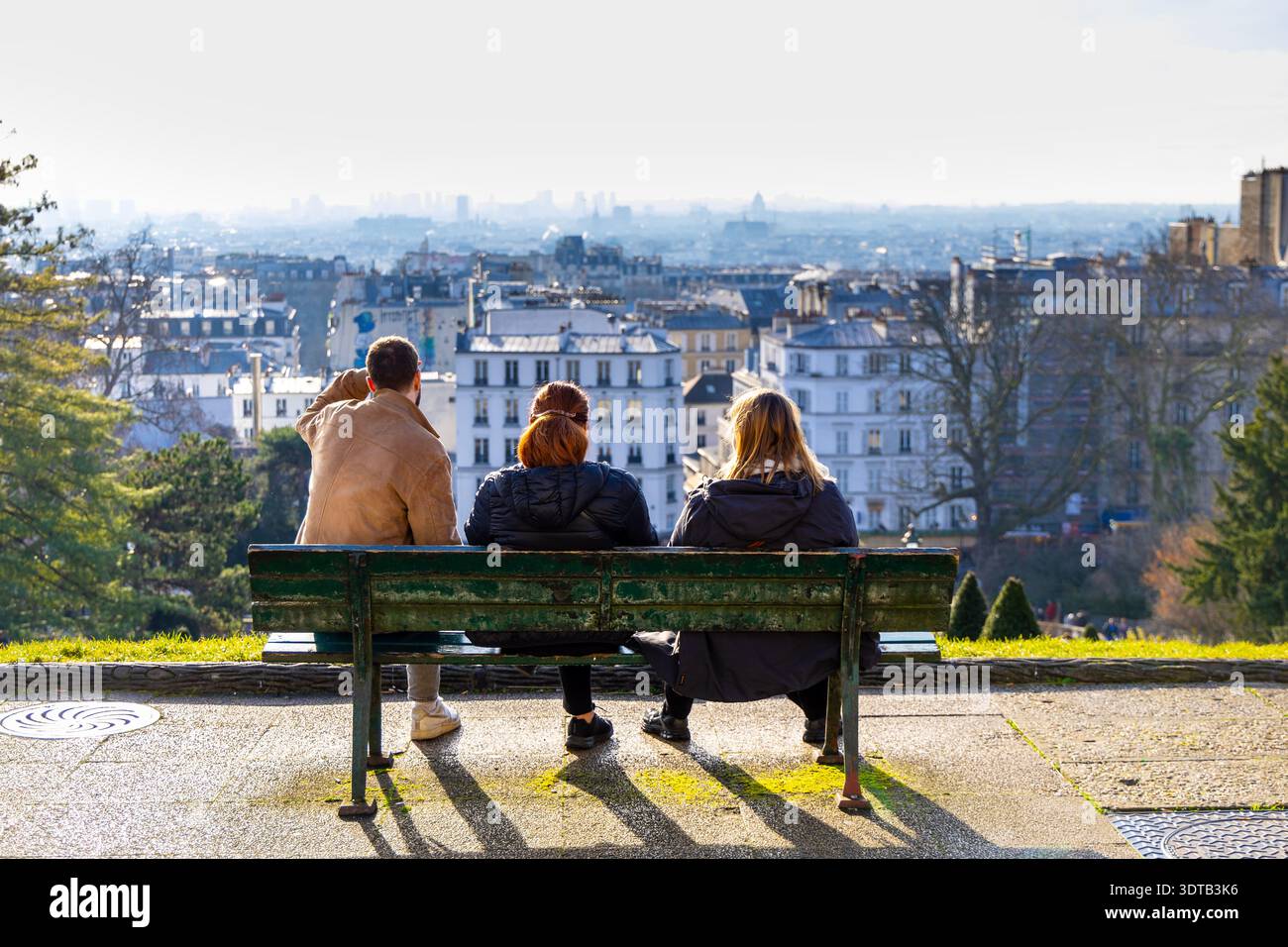 Touristen, die auf der Bank sitzen und einen Blick auf Paris vom Place Louise Michel, Montmartre, Paris, Frankreich haben Stockfoto