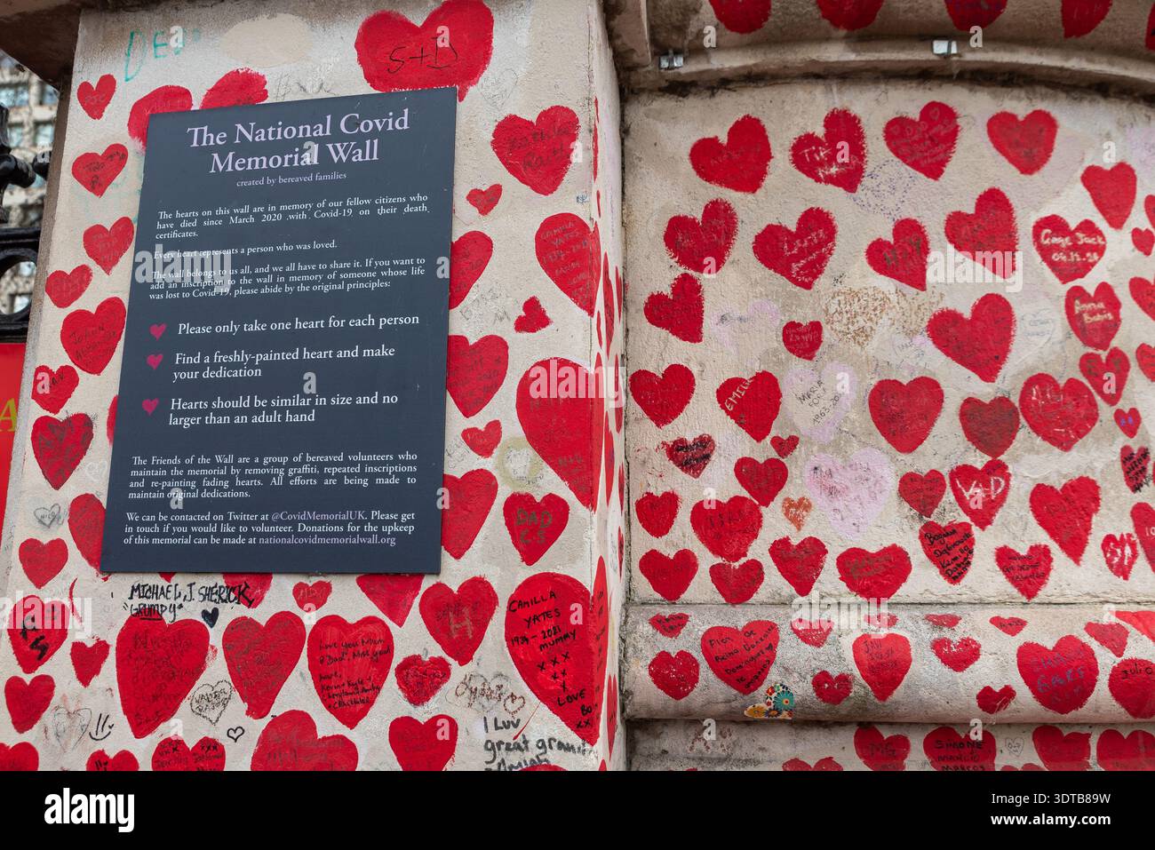 National COVID Memorial Wall in Lambeth, London, Vereinigtes Königreich. Rote Herzen auf eine Wand gezeichnet, die jeden Tod durch COVID 19 repräsentiert. Plaque mit Anweisungen Stockfoto