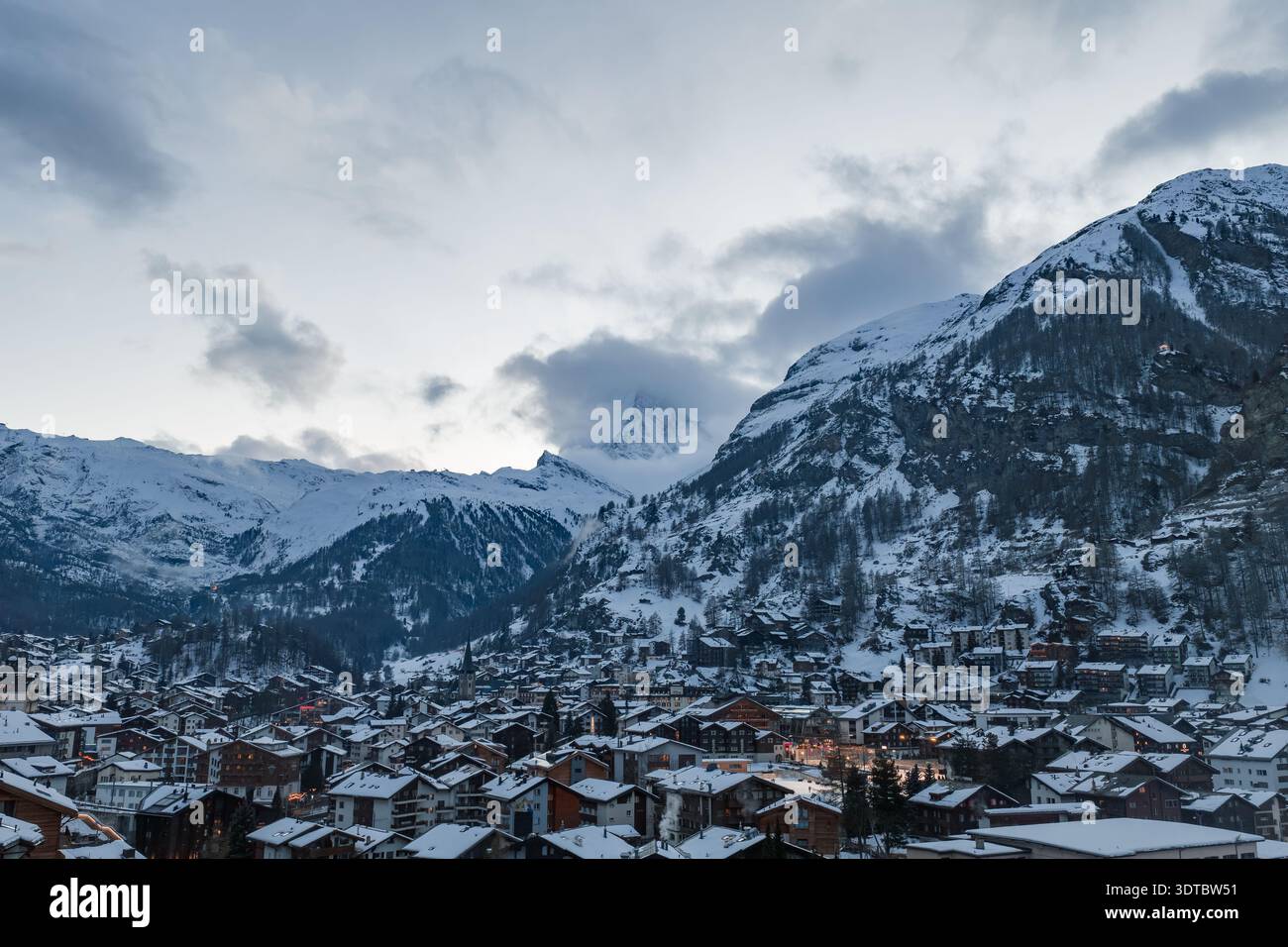 Zermatt in der Winterdämmerung mit Matterhorngipfel und Kirchturmbeleuchtung Stockfoto
