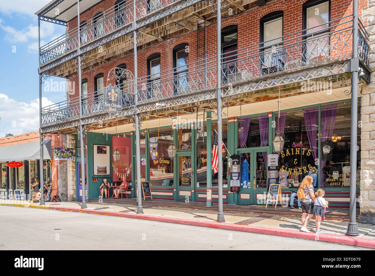 Arkansas, 21. September 2024 - zweistöckiges Backsteingebäude mit kunstvollen Eisenbalkonen und Ladenfronten in einer sonnigen Straße in New orleans. Stockfoto