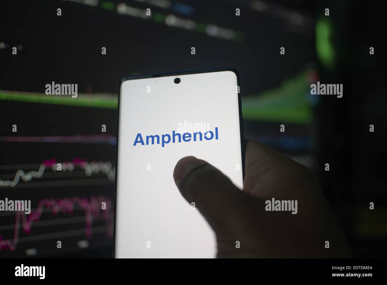 Ein Telefon mit dem Amphenol-Logo vor den Börsencharts Stockfoto