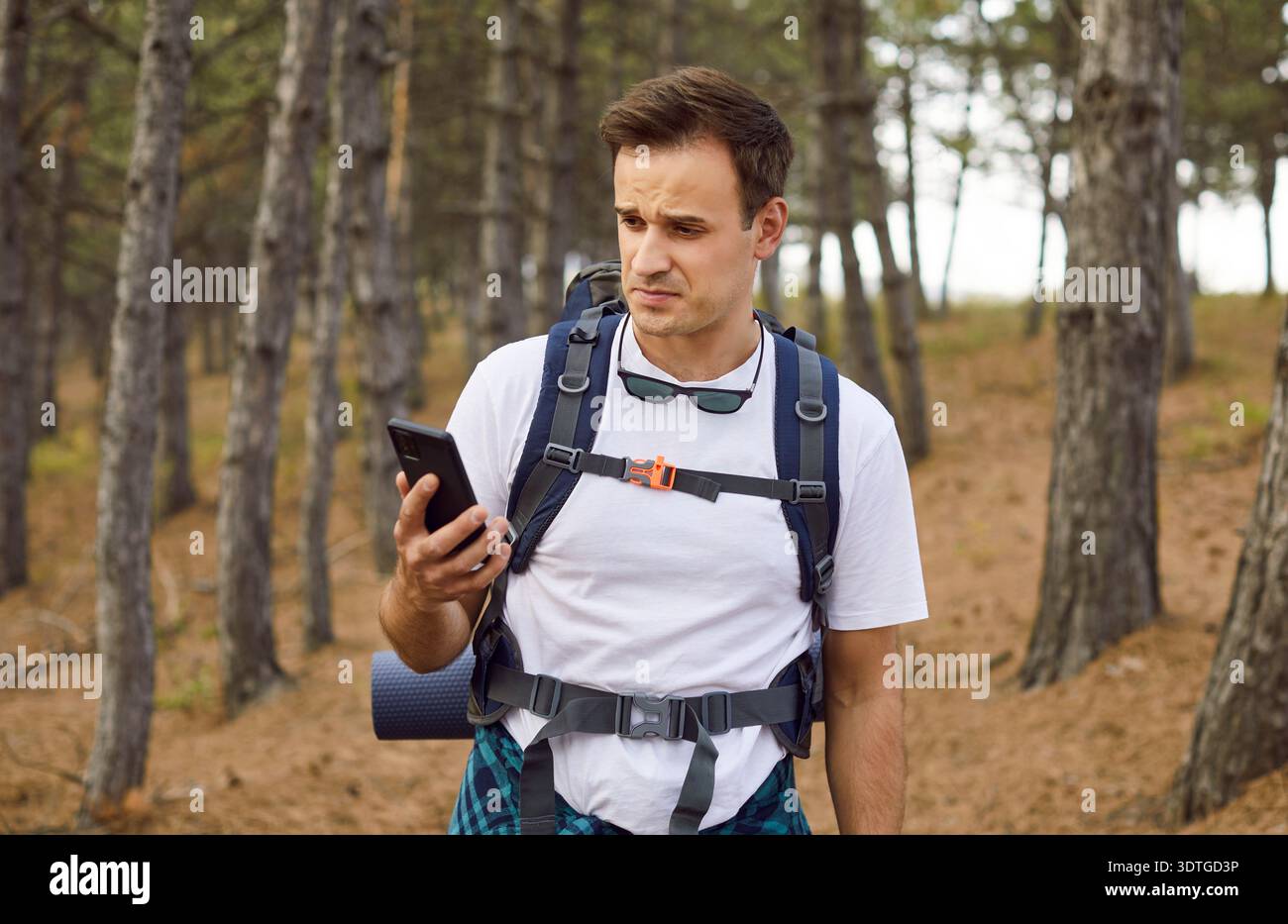 Wanderer sucht nach verlorenem Smartphone-Signal im Wald, um Geolokation zu finden Stockfoto