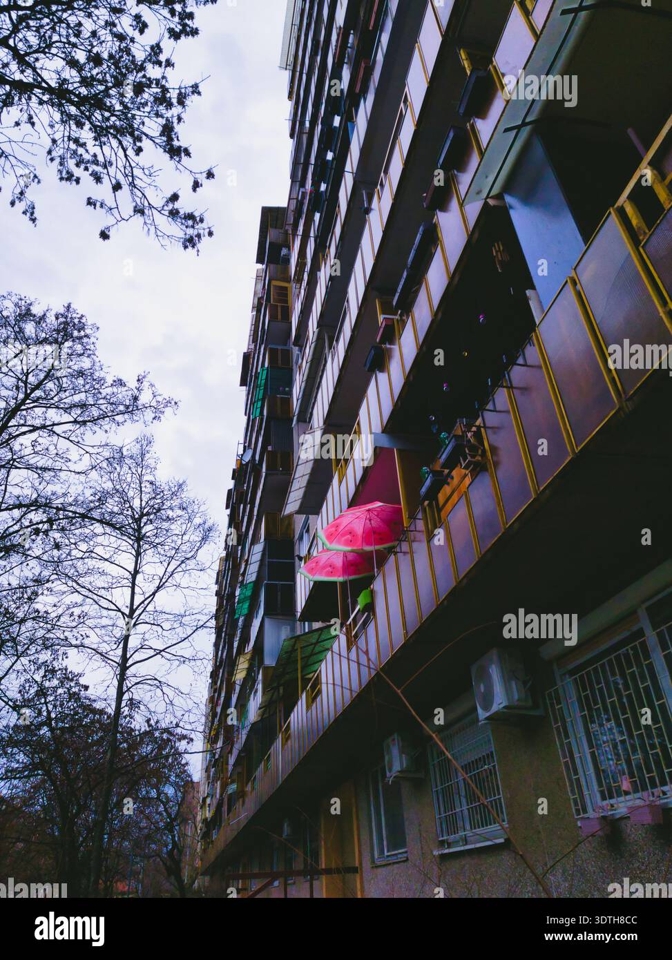 Ein beeindruckender vertikaler Blick auf ein Hochhaus mit farbenfrohen pinkfarbenen Regenschirmen. Dieses Bild zeigt den Schnittpunkt von privatem Haus Stockfoto