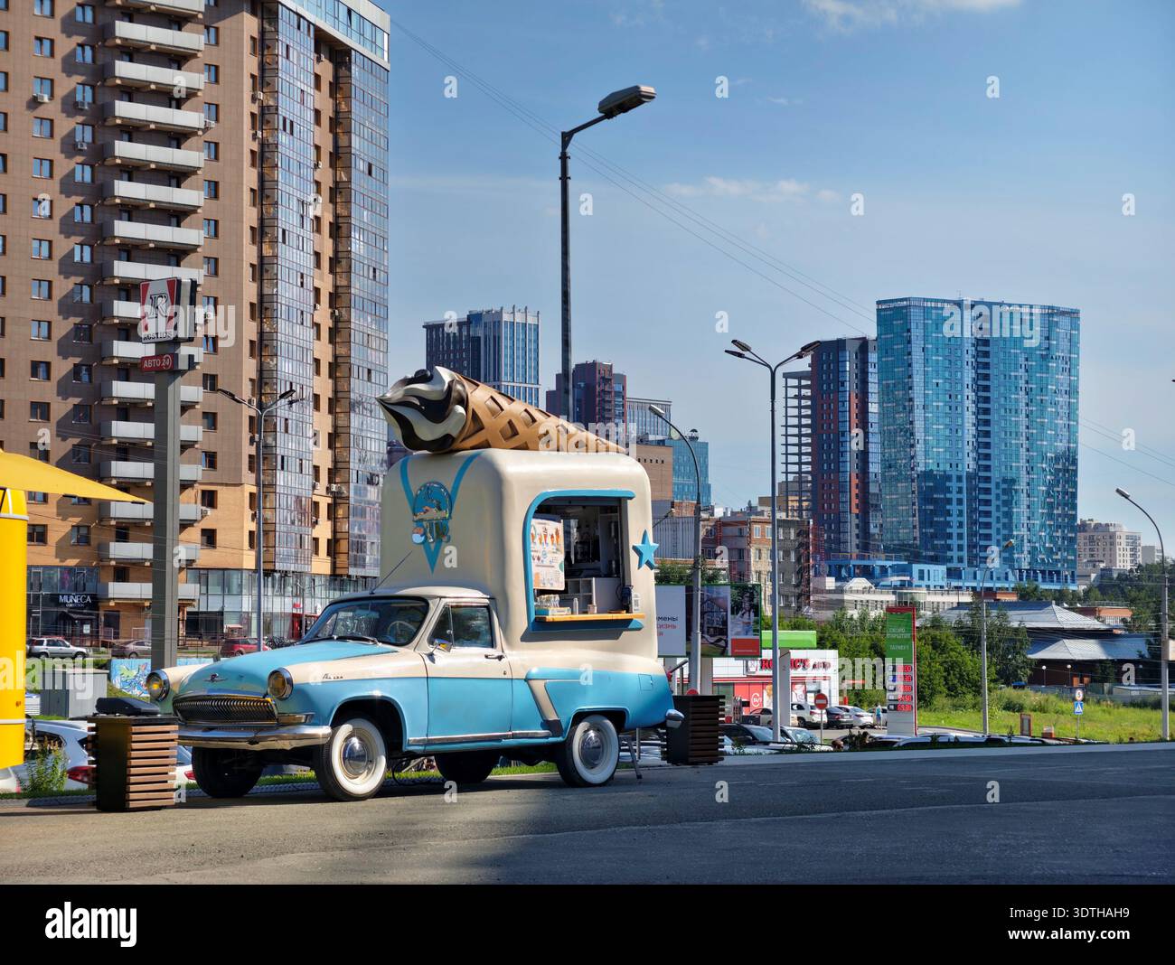 Nowosibirsk, Russland - 31. Juli 2024: Eine Snackbar auf Rädern. Eine Eisdiele in einem alten Volga-Oldtimer. Im Hintergrund befindet sich das Hochhaus Stockfoto