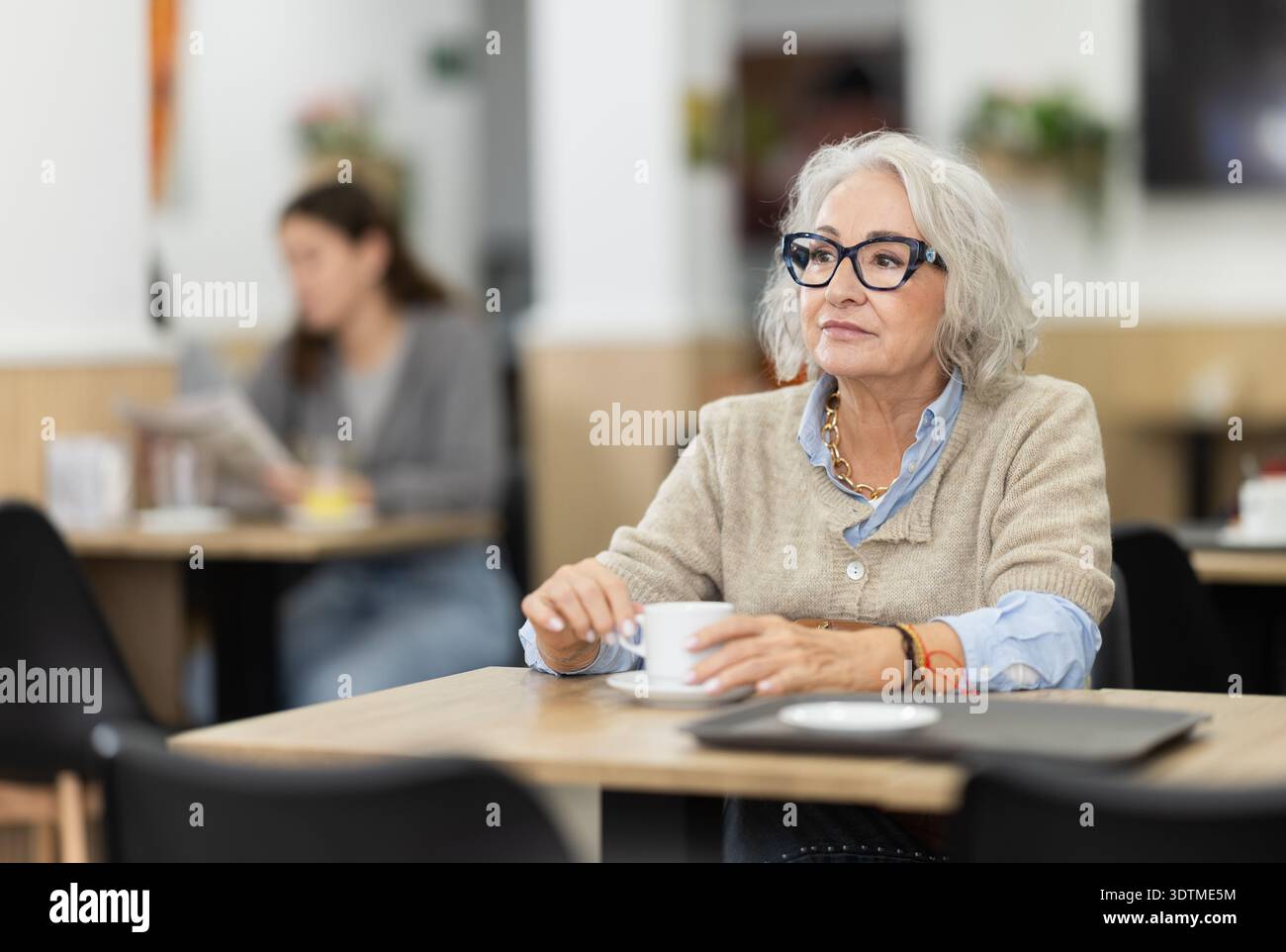 Seniorin sitzt allein am Tisch im Café und trinkt duftenden Kaffee Stockfoto