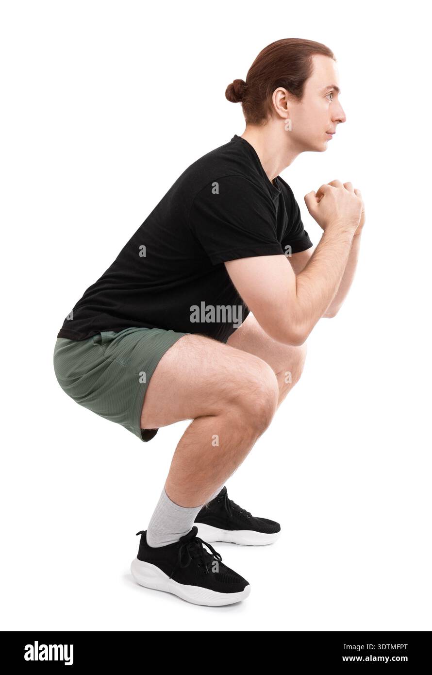 Seitenansicht eines fitten jungen Mannes mit einem Brötchen, der eine tiefe Hockübung durchführt. Isoliert auf weißem Hintergrund. Hochwertige Fotos Stockfoto