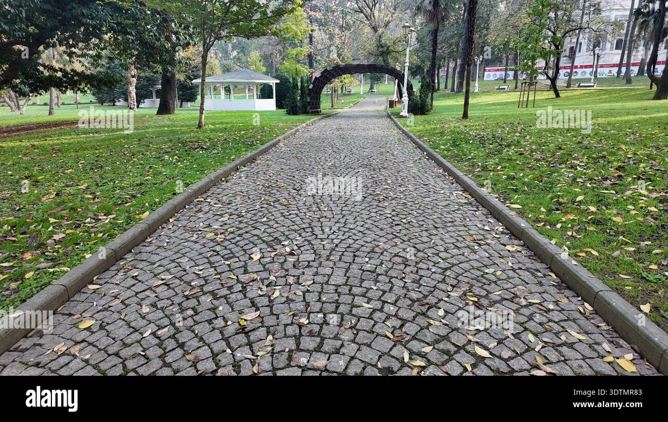 Der Weg führt durch einen Park mit Grün und einem Pavillon Stockfoto