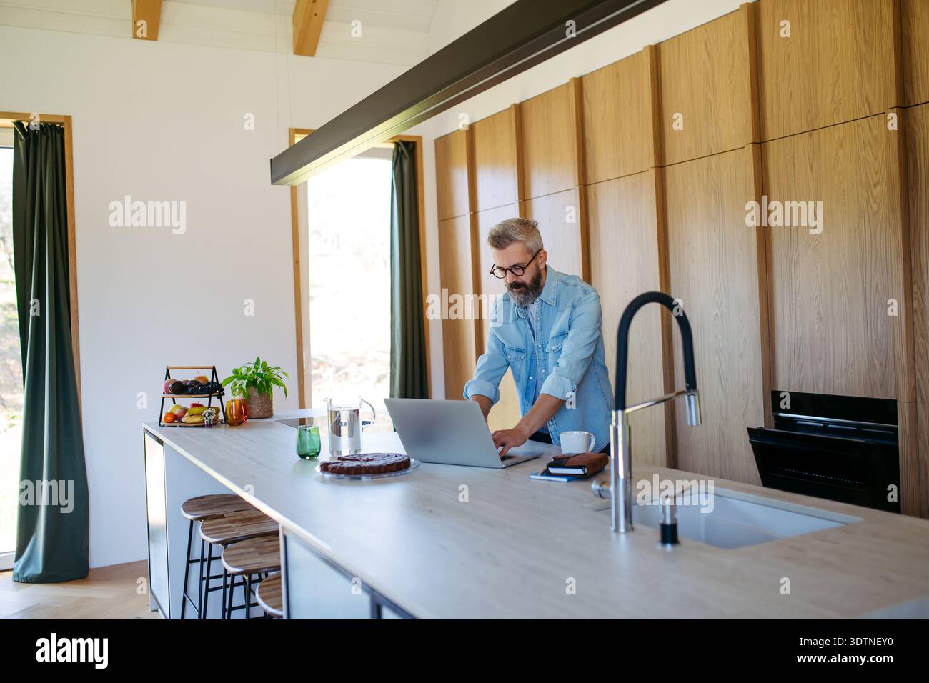 Mann, der von zu Hause aus arbeitet, während er telefoniert. Stockfoto