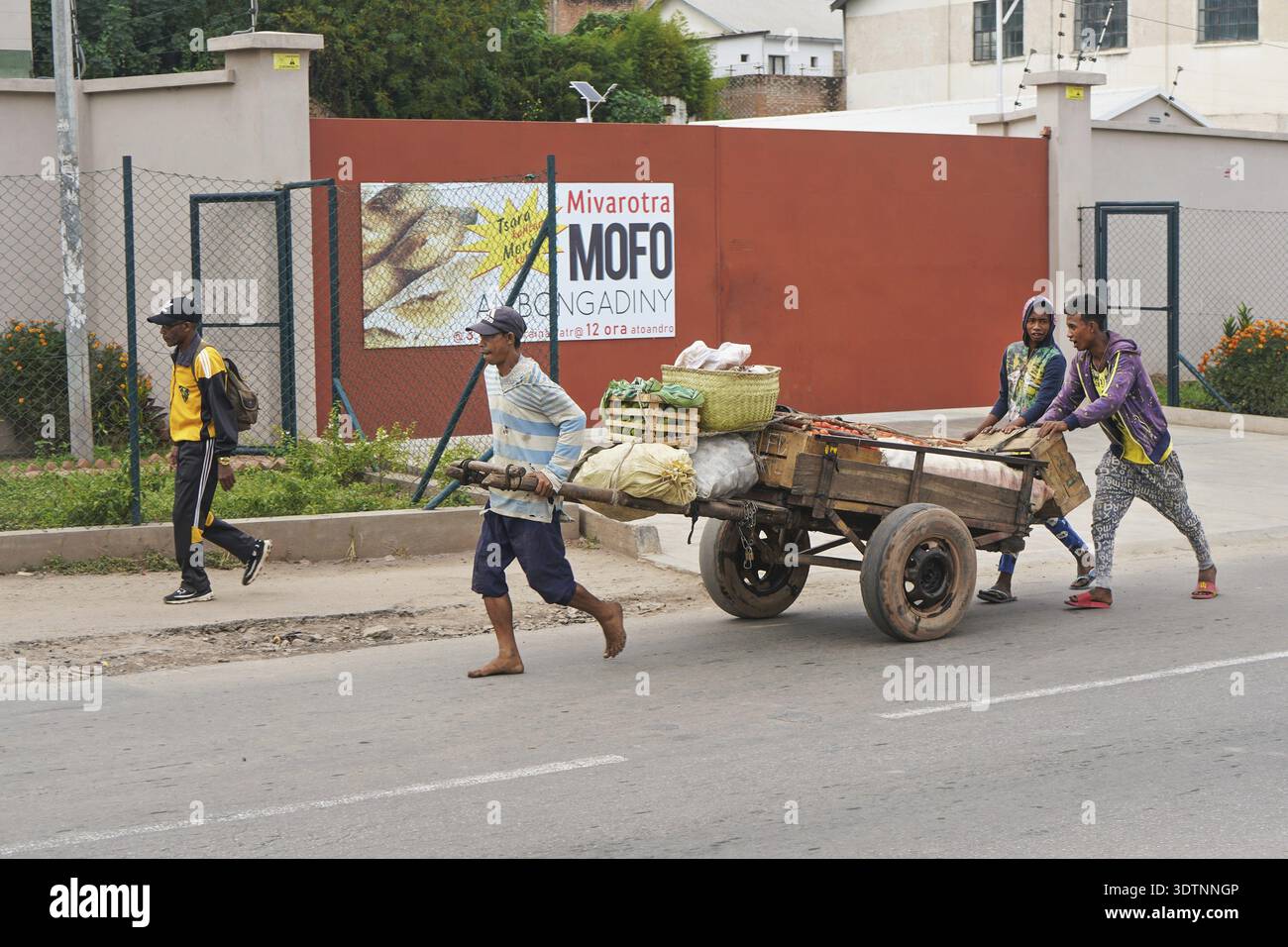 Antananarivo, Madagaskar - 24. April 2019: Unbekannter madagassischer Mann zieht Holzkarren mit Obst auf der Hauptstraße. Es gibt nicht viele Geschäfte in Madagaskar Stockfoto