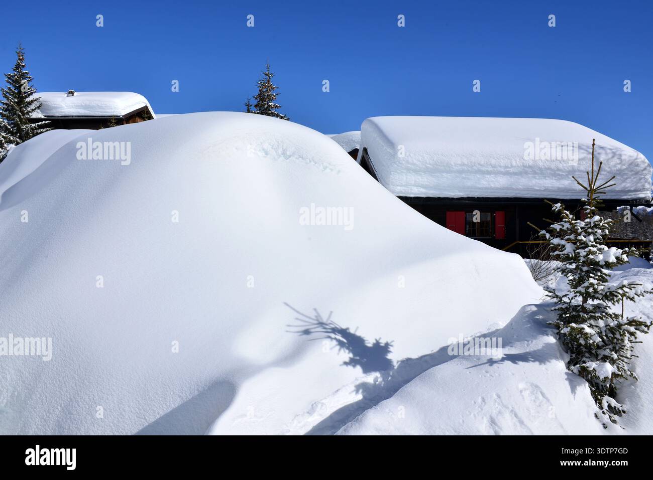 Chalets unter tiefem Schnee mit blauem Himmel Stockfoto