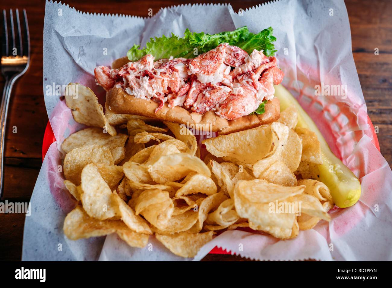 Hummerrolle mit Chips und Gurke auf dem Tisch Stockfoto