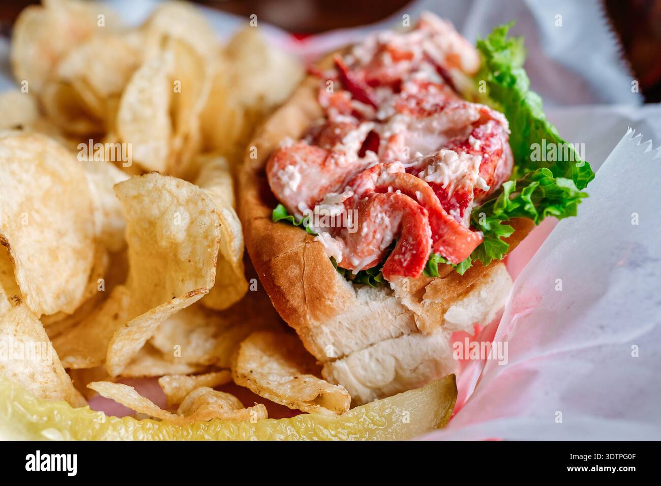 Hummerrolle mit Chips und Gurke auf dem Tisch Stockfoto