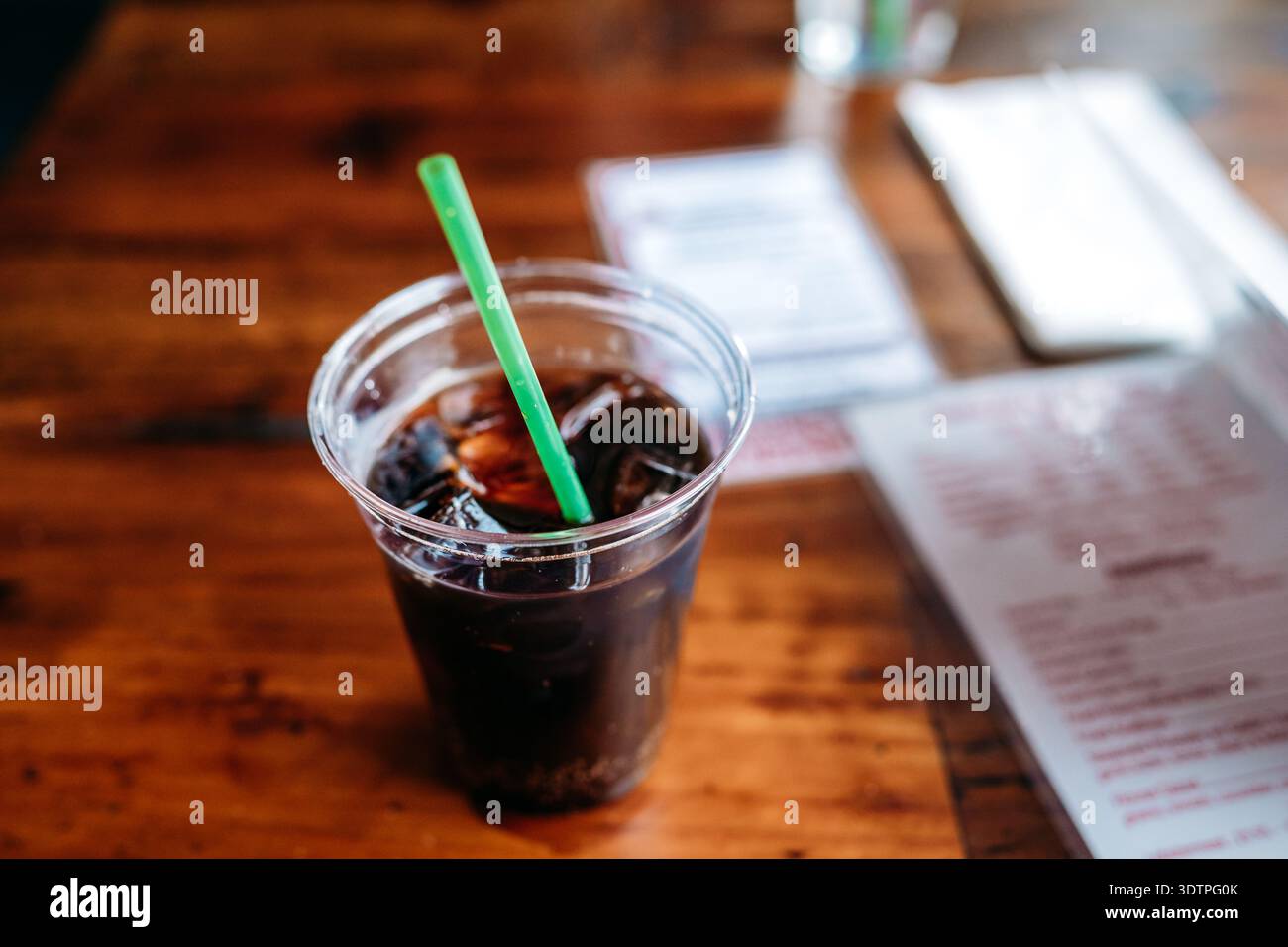 Eiscola in Plastikbecher auf Holztisch Stockfoto