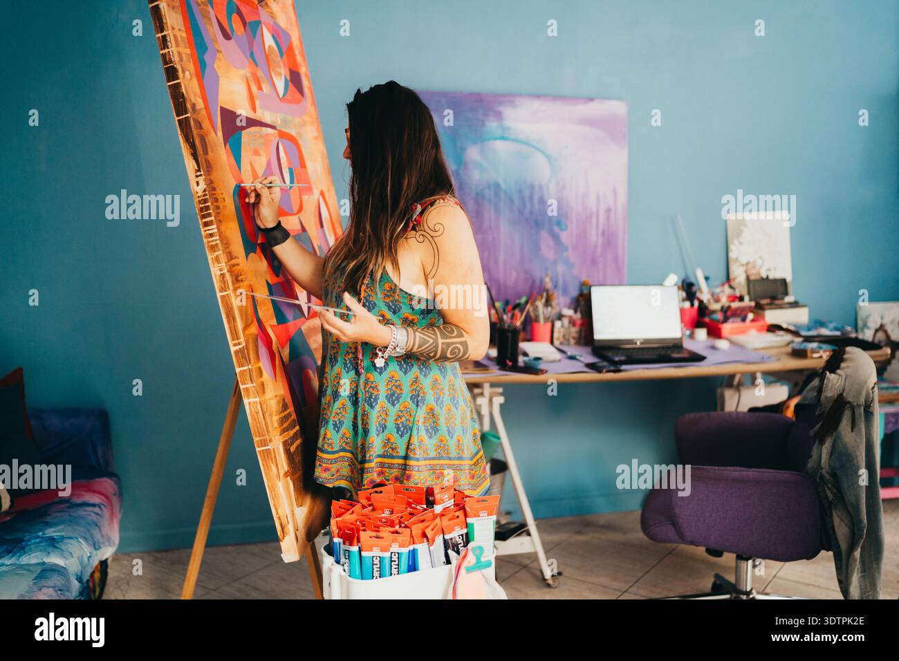 Frau malt auf Staffelei in ihrem bunten Kunststudio Stockfoto