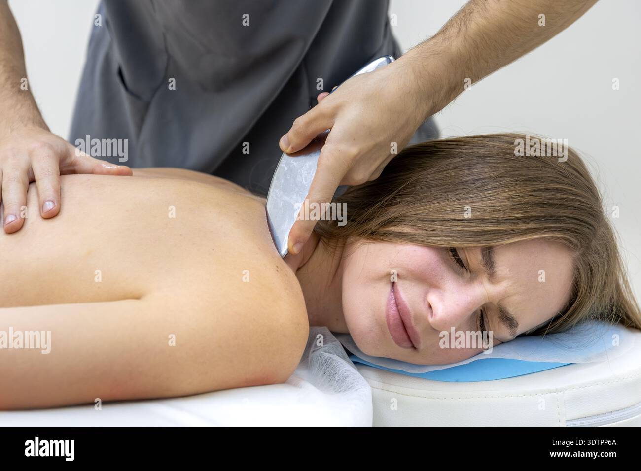 Der Patient fühlt sich während der IASTM-Werkzeugtherapie mit dem Arzt unwohl. Schmerzlinderung. Stockfoto