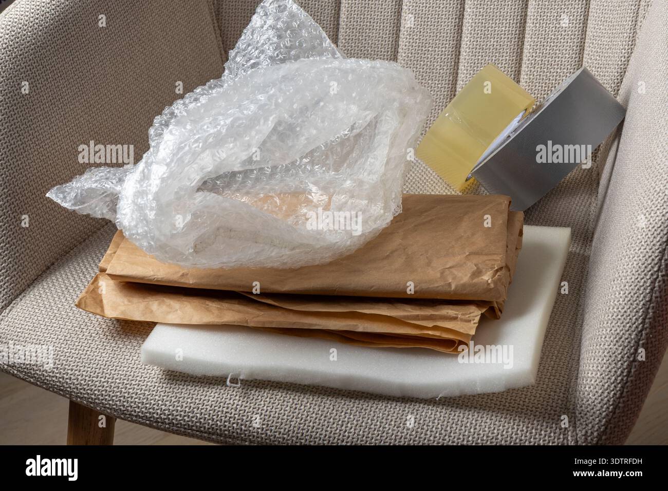 Ein Stapel von Verpackungsmaterialien, einschließlich Luftpolsterfolie, braunem Papier und Schaumstoffpads, bereit für den Versand oder Transport. Stockfoto