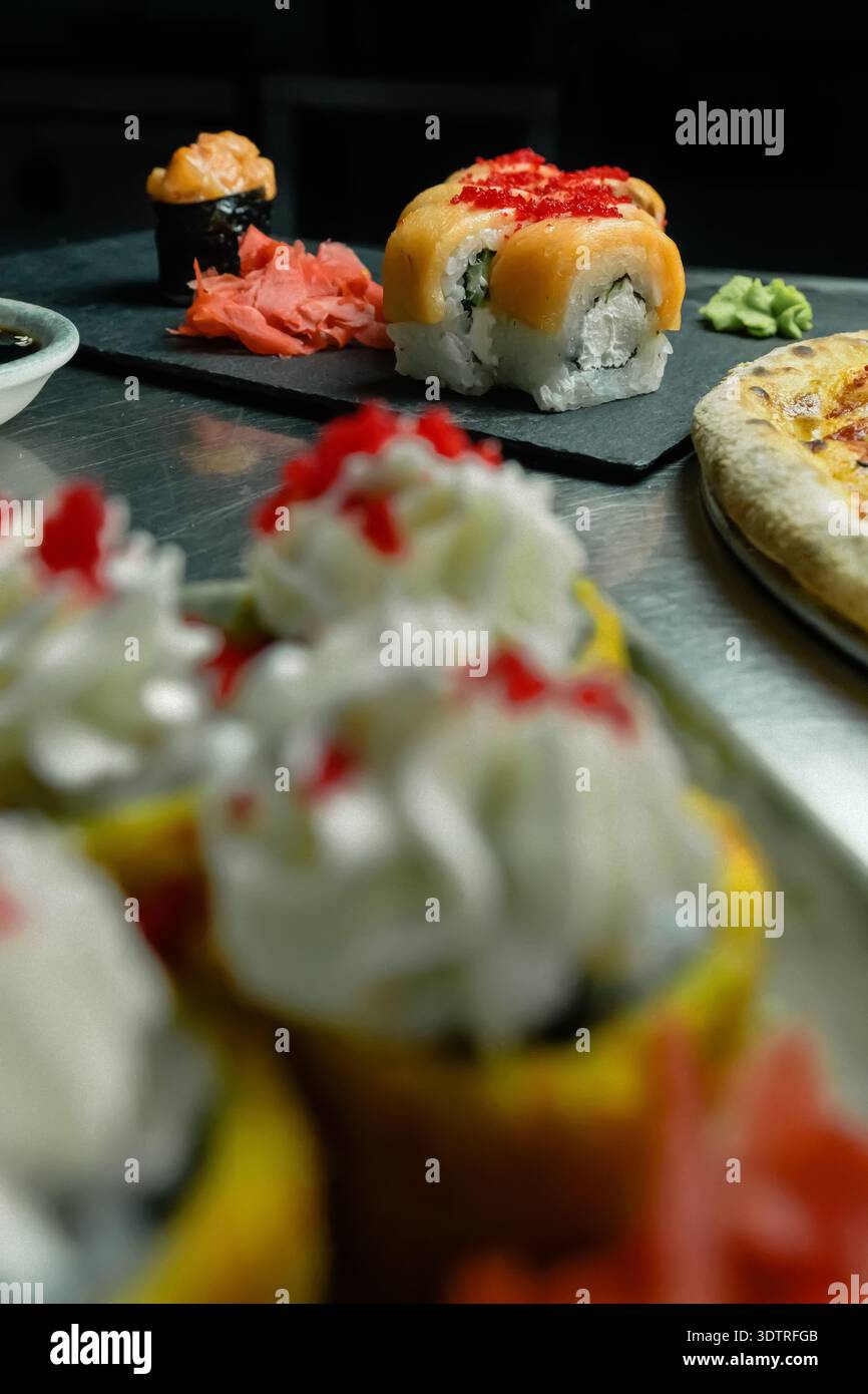 Eine Auswahl an farbenfrohen Sushi Rolls und Köstlichkeiten, die kunstvoll auf einem Teller angeordnet sind und die lebendigen Aromen und Texturen der japanischen Küche zeigen Stockfoto