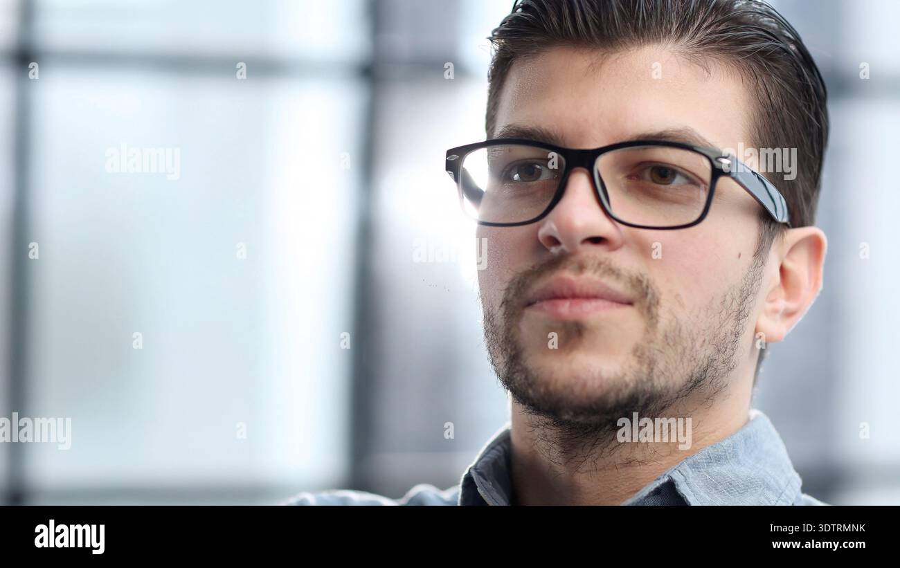 Das Gesicht eines Mannes in Nahaufnahme mit einer Brille sieht nachdenklich weg Stockfoto