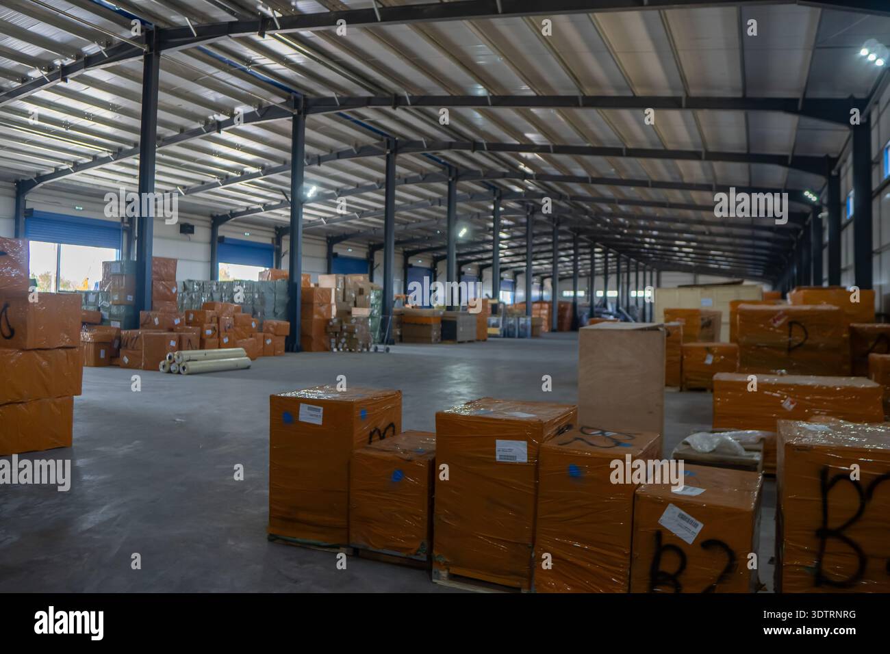 Geräumiges Lager mit gestapelten Boxen und Verpackungsmaterialien, das auf den Vertrieb in einer industriellen Umgebung wartet Stockfoto