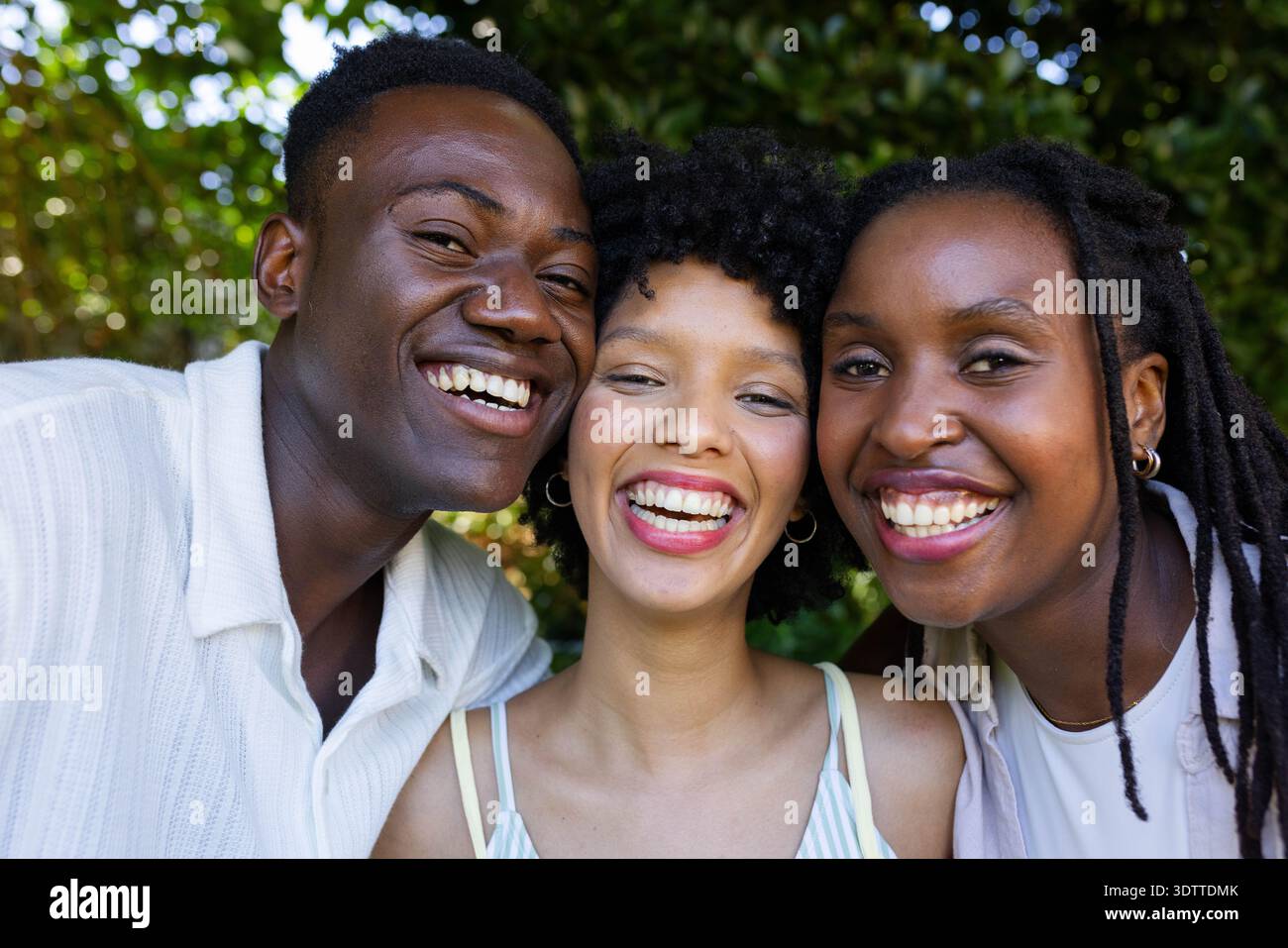 Afroamerikanische Freunde lachen in der Nähe des Parks, Button-up-Hemd, gestreiftes Tanktop, Creolen-Ohrringe Stockfoto