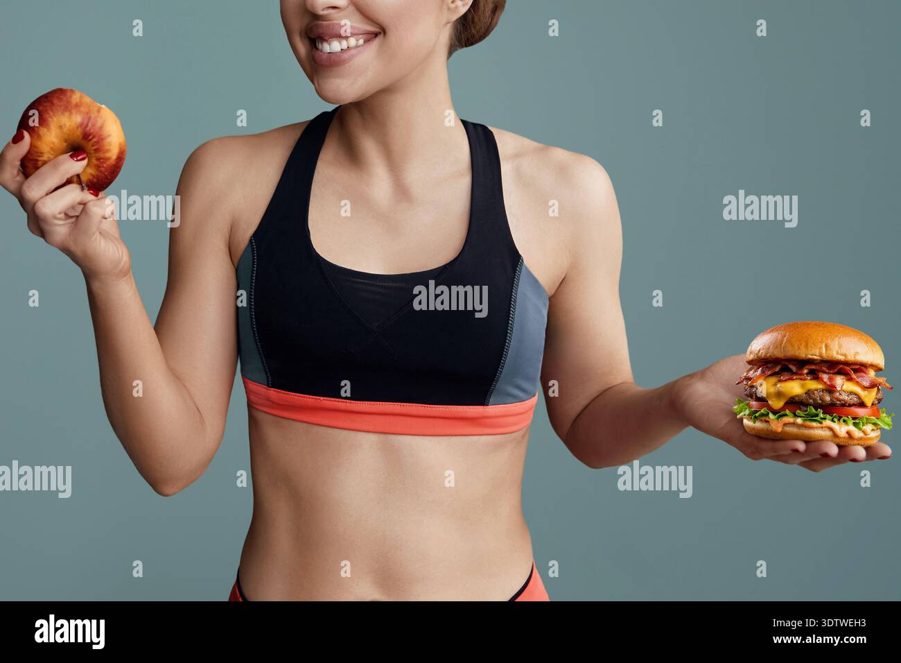 Frau, die zwischen Apfel und Hamburger wählen kann. Diät-Konzept. Stockfoto