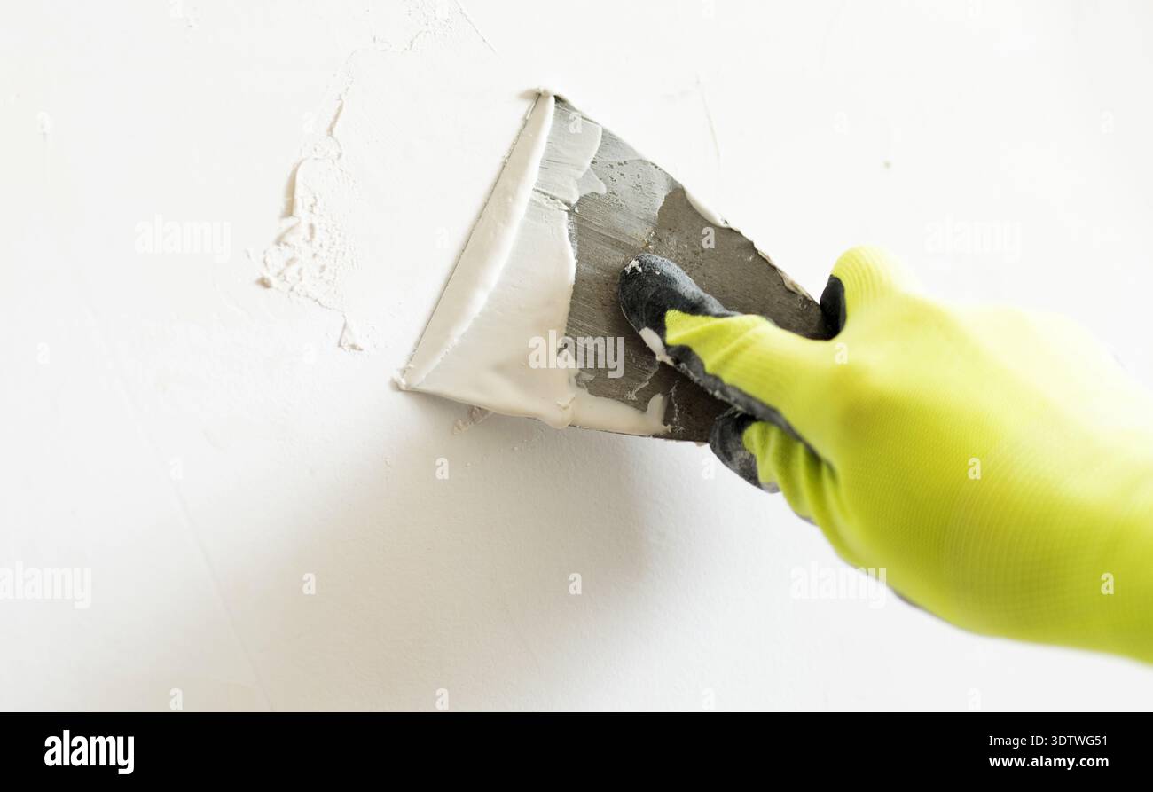 Arbeiter, der beim Glätten der Wand mit Einem Spatel das Putty aufträgt Stockfoto