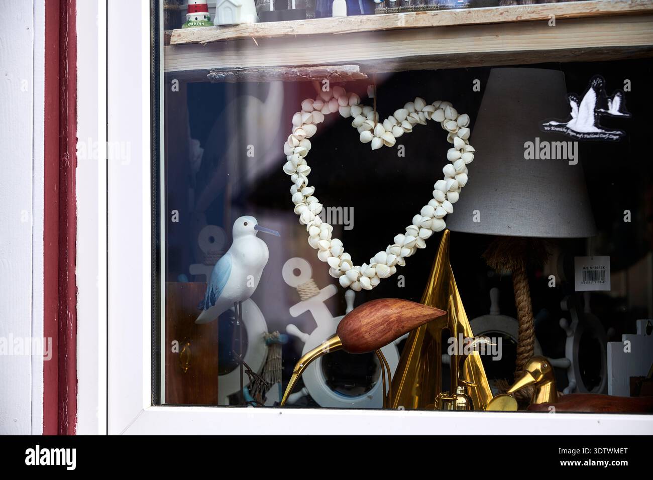 Ein detaillierter Blick auf ein Schaufenster mit einer Auswahl an nautischen und küstenbezogenen Dekorationen. Das Zentrum dominiert ein herzförmiger Kranz cr Stockfoto