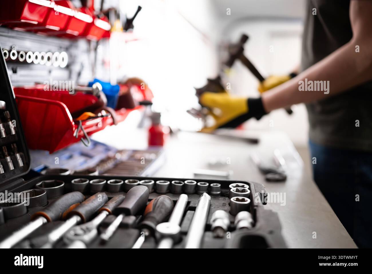 Servicemitarbeiter Repariert Autoteile Mit Hammer An Werkbank In Der Garage Stockfoto