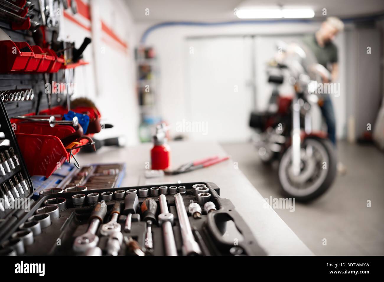 Mann Mit Klassischem Motorrad In Der Garage, Das Motorrad Regelmäßig Überprüft Und Gewartet Stockfoto