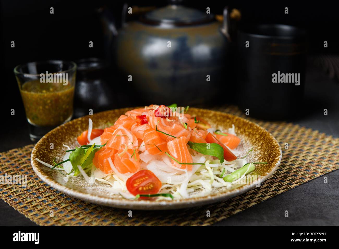 Frische Sashimi-Scheiben vom Lachs, serviert auf einem Bett mit knusprigem Gemüse, kombiniert mit einem Dressing nach japanischer Art für einen erfrischenden Salat mit Meeresfrüchten. Stockfoto