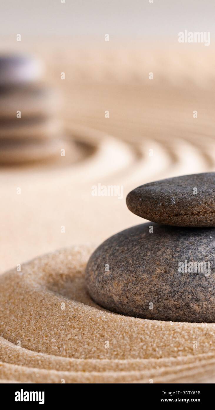 Gestapelte Steine auf Sand mit Kräuseln in einem Zen-Garten während der Tageslichtstunden Stockfoto