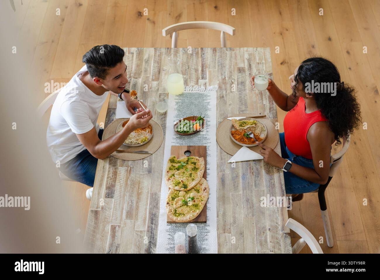 Auf dem rustikalen Holztisch werden Fladenbrote, Salatschalen und helle Getränke im Speisesaal ausgestellt Stockfoto