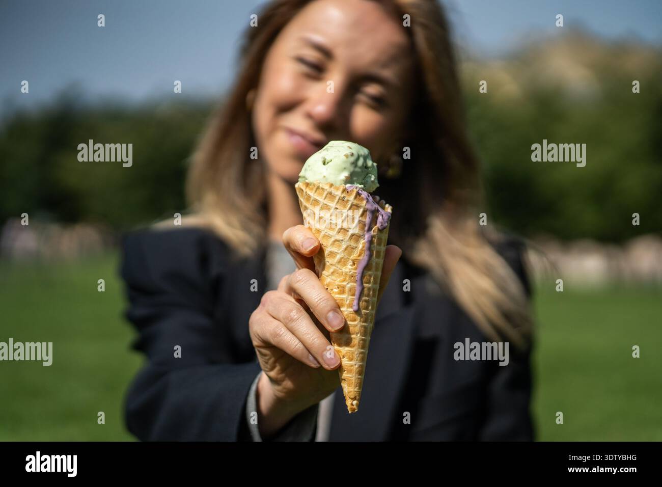 Fröhliche positive Frau posiert mit Eis in der Hand und genießt erfrischende Leckereien am Sommertag. Stockfoto