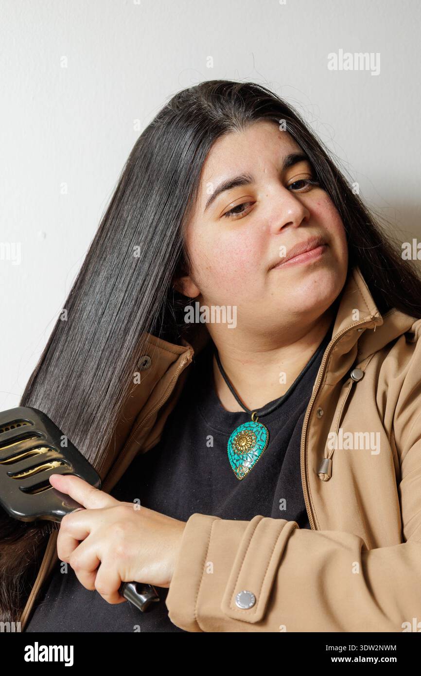 Eine Person bürstet langes dunkles Haar mit einem breiten Kamm. Stockfoto