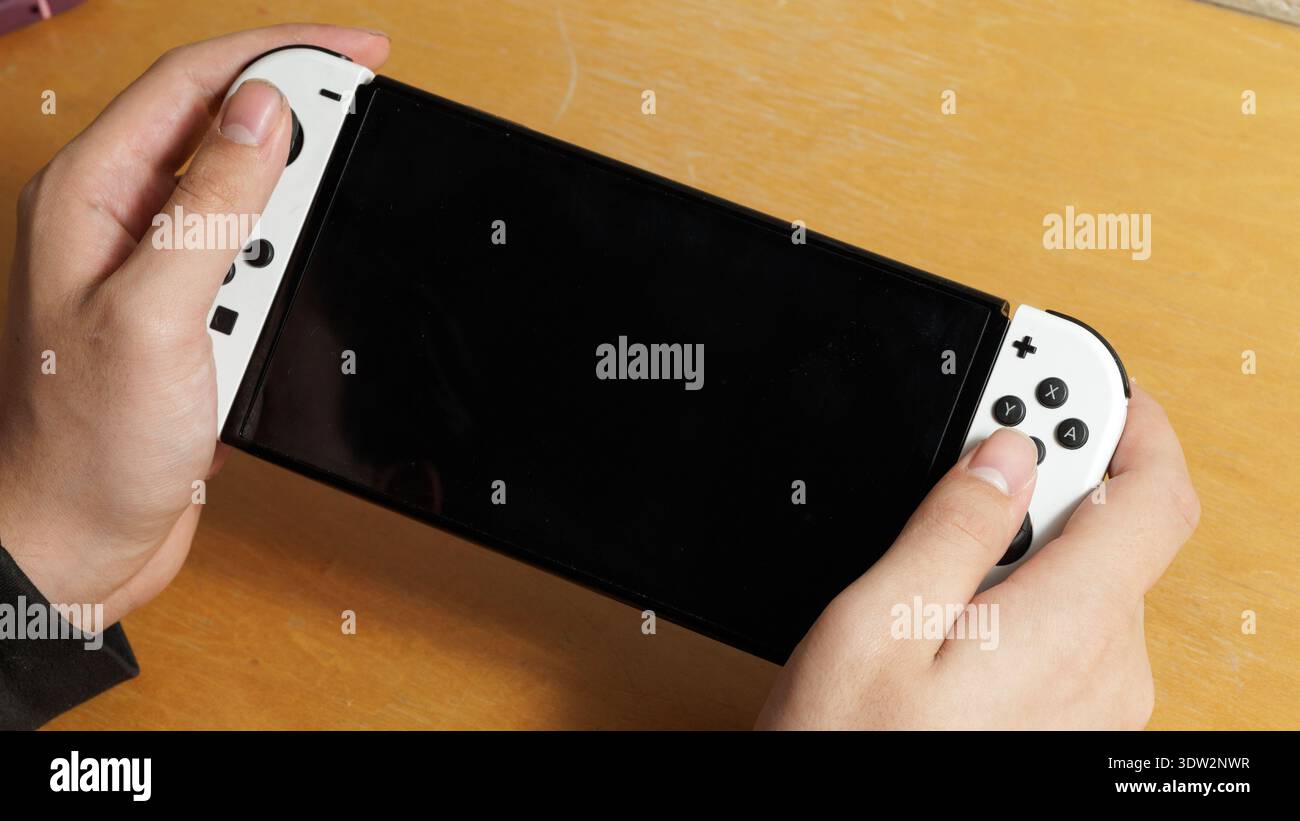 In dieser Abbildung sind Hände, die einen Nintendo Switch im Handbetrieb halten. Stockfoto