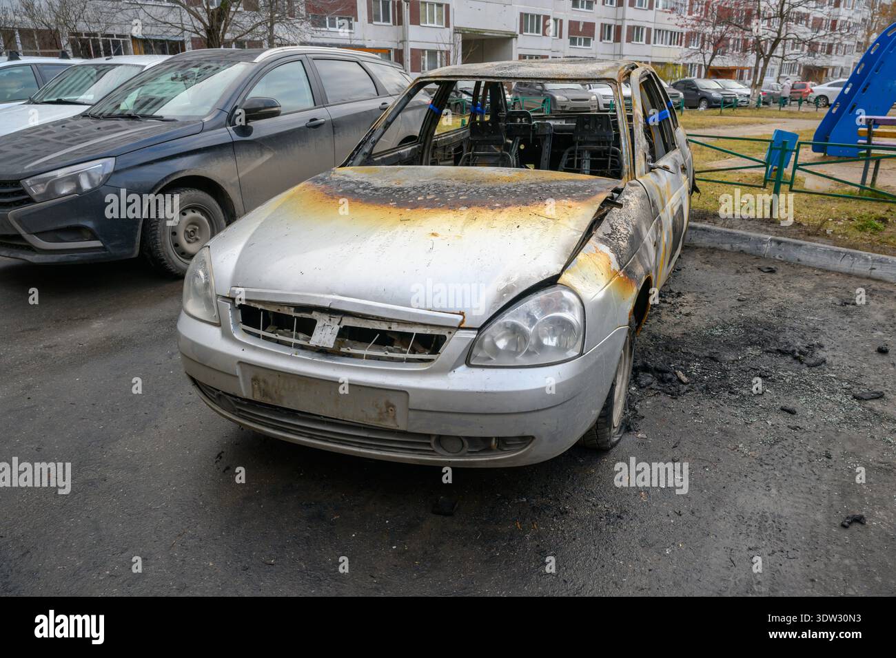 Verbranntes Auto sitzt verlassen auf einer Straße der Stadt und sieht Fahrzeuge in der Nähe Stockfoto
