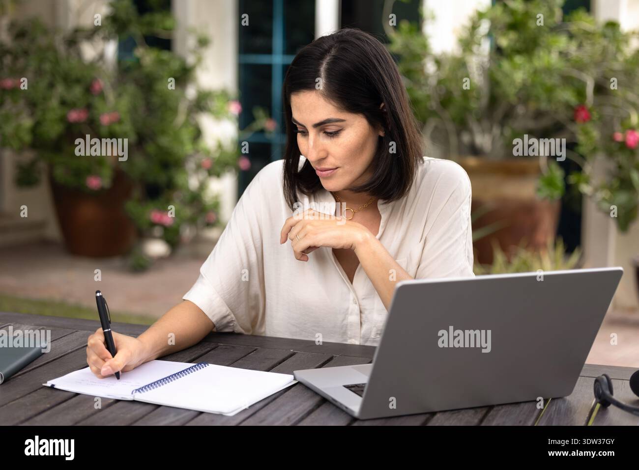 Fokussierte Erwachsene Studentin, die im Copybook am Laptop schreibt Stockfoto