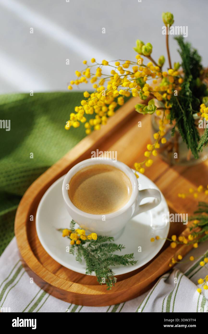 Frisch gebrühter Kaffee mit Mimosa-Blüten auf einem Tablett Stockfoto