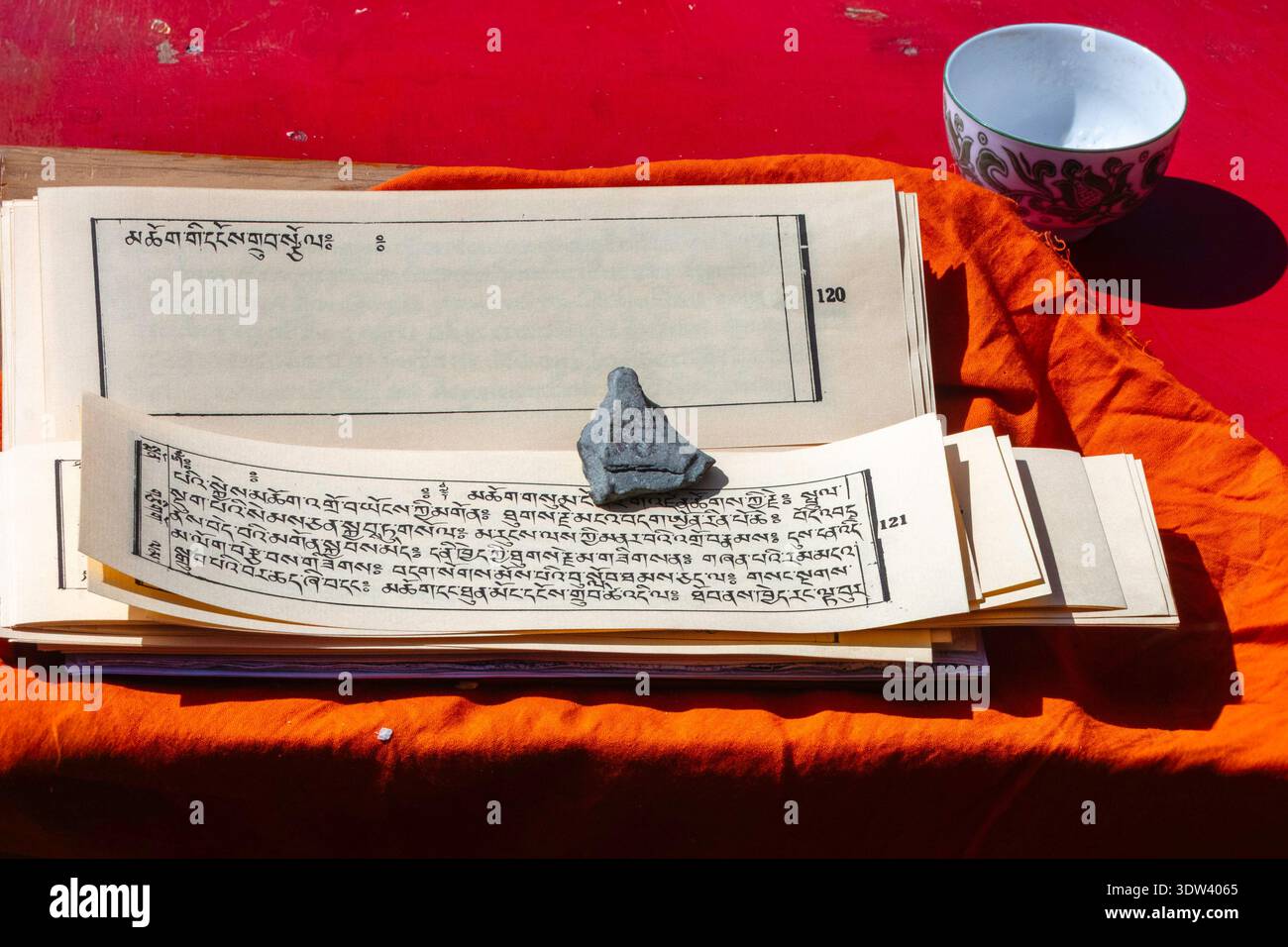 Eine Sammlung heiliger tibetischer Manuskripte liegt auf einem lebendigen Tuch, das kulturelles Erbe und spirituelle Weisheit symbolisiert. Stockfoto