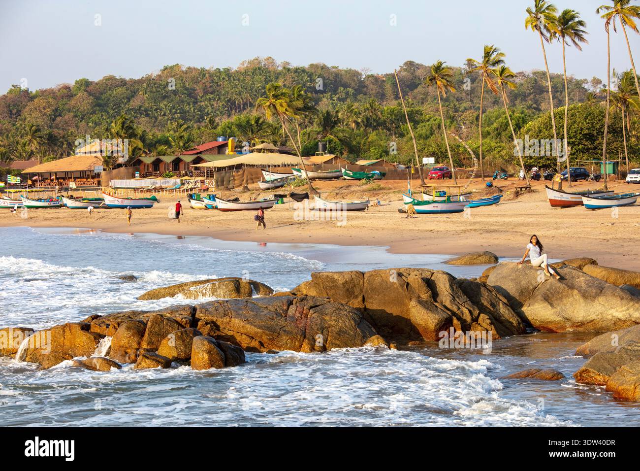 Eine ruhige Strandszene mit Fischerbooten und Palmen unter einem sonnigen Himmel in Goa, Indien. Stockfoto