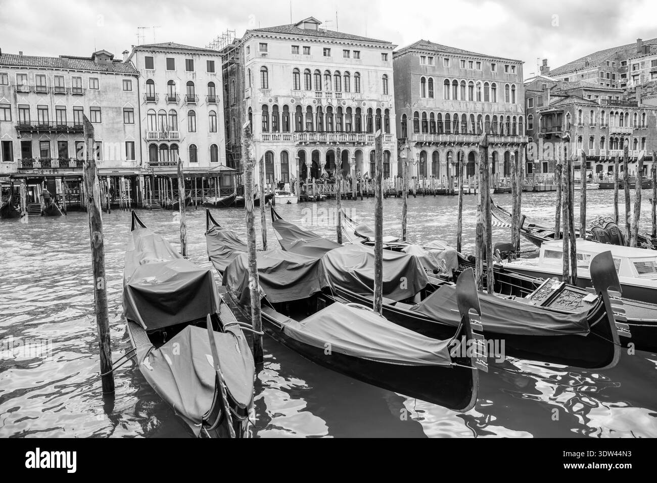 Überdachte Gondeln gleiten ruhig entlang eines venezianischen Kanals, eingerahmt von historischer Architektur. Stockfoto