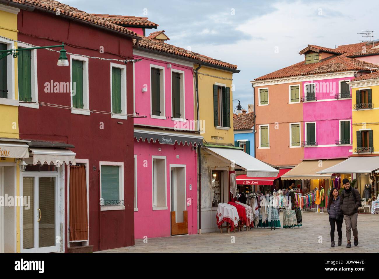 Eine lebhafte Straße in Burano, Venedig, mit farbenfrohen Gebäuden und lokalen Geschäften. Stockfoto