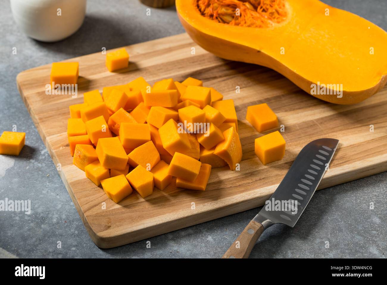 Biologisch gewürfelter Butternusskürbis auf einem Schneidebrett Stockfoto