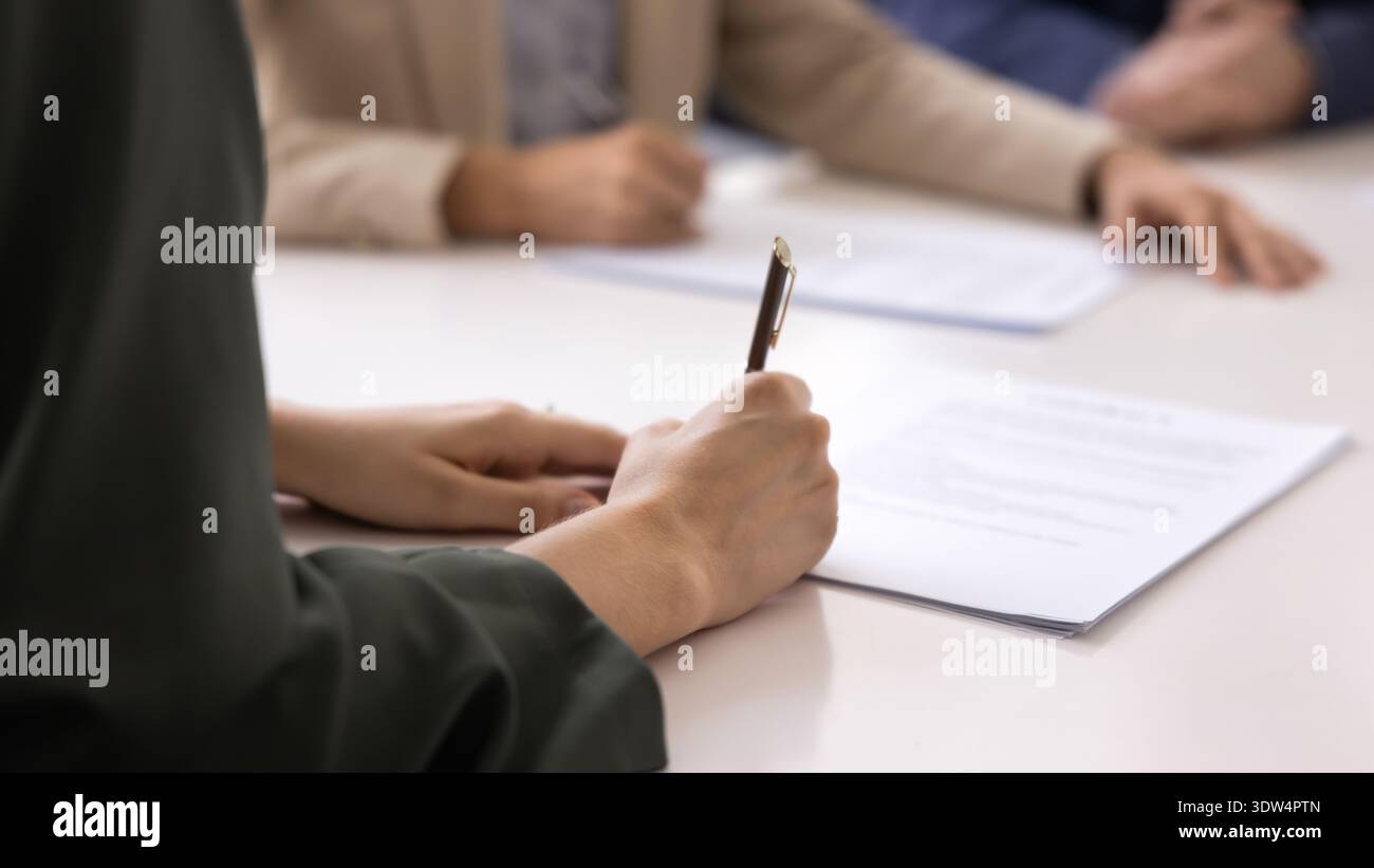 Nahaufnahme einer Frau, die während eines formellen Treffens einen Vertrag unterschreibt Stockfoto