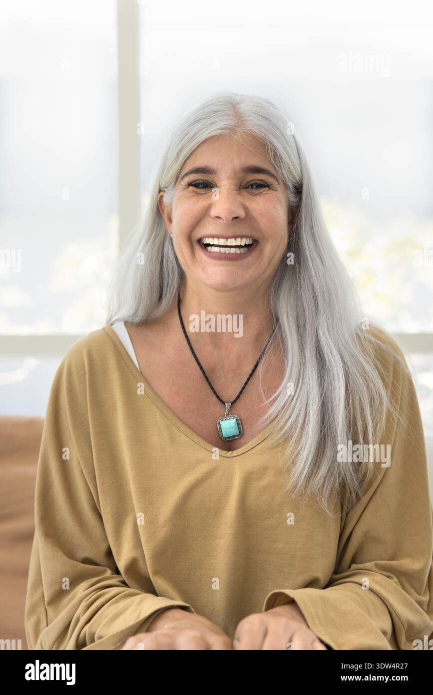 Lachende reife Frau posiert für die Kamera auf der Couch Stockfoto
