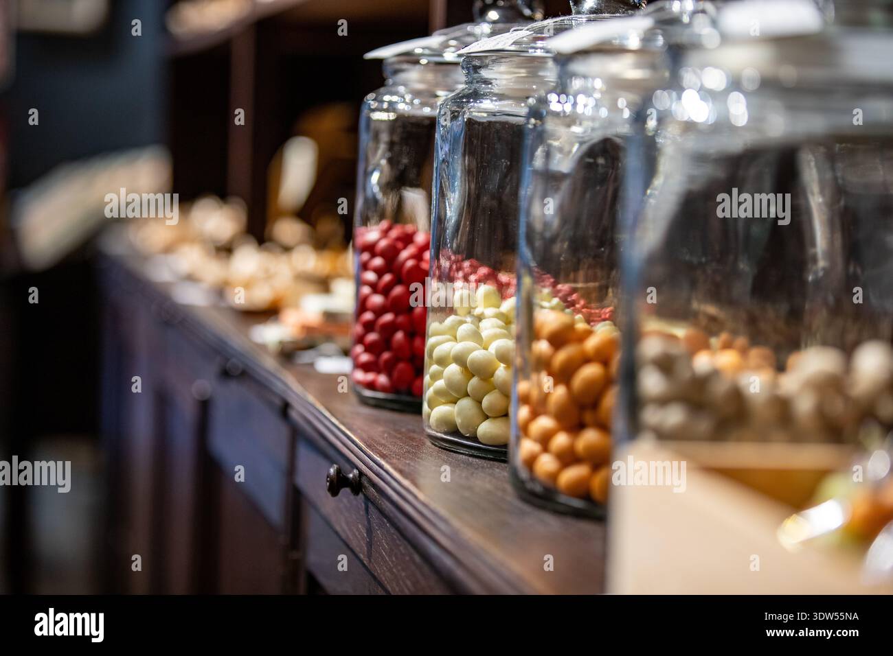 Glasgläser mit Süßigkeiten, glasierte Nüsse auf einem Display Stockfoto
