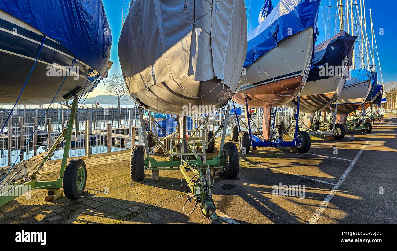 Uberlingen, Deutschland - 26. Dezember 2024. Yachten in Schutzabdeckungen auf speziellen Hubwagen, Metallkonstruktionen mit Rädern, am Pier für die Winterstraße Stockfoto