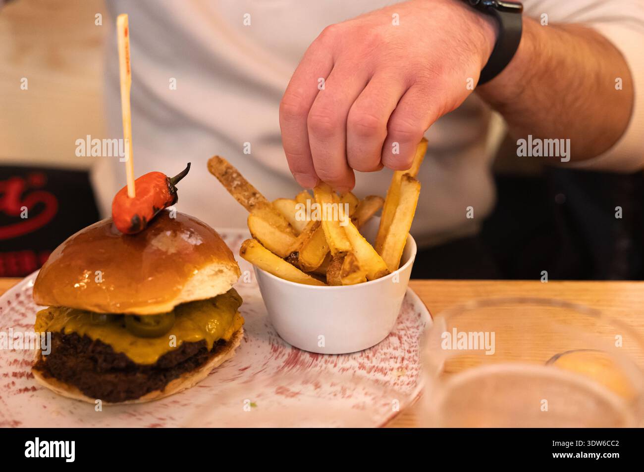 Entspannte Umgebung, in der der Mann seinen Burger und Pommes friedlich genießt Stockfoto